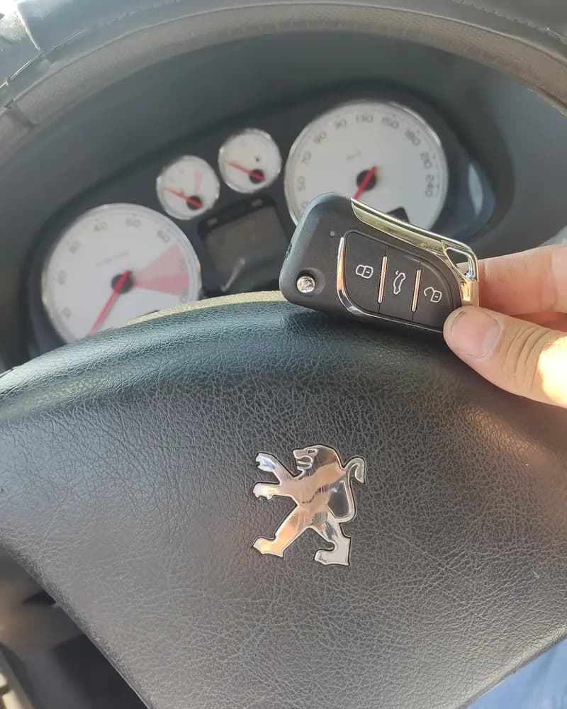 Chave canivete nova na mão, diante do volante de um Peugeot 307