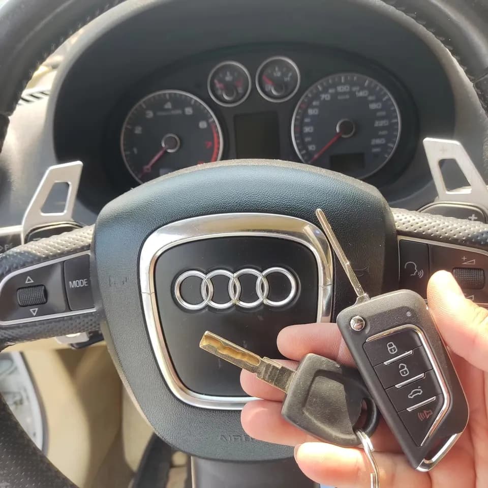 Chave canivete nova e a chave antiga diante do volante de um Audi A3 Sportback
